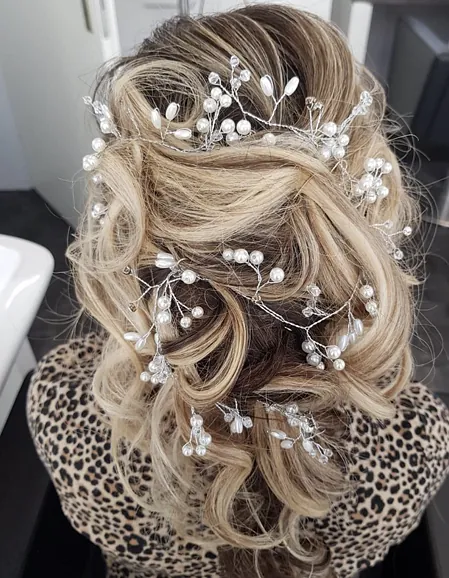 Weibliche Hochsteckfrisur. Blonde Haare und weiße Verzierung.