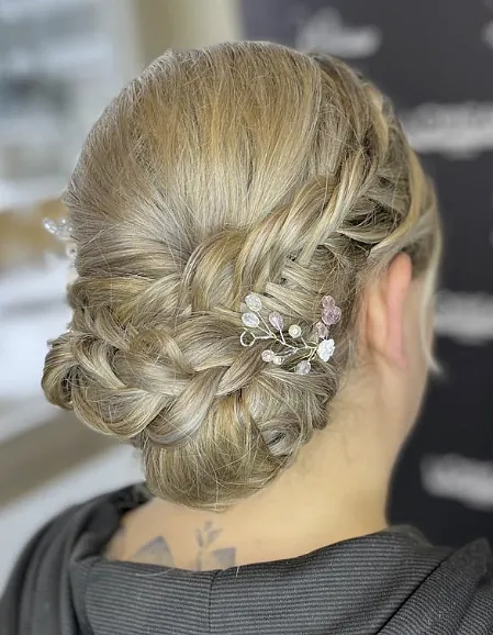 Weibliche Hochsteckfrisur. Blonde Haare und rosa Verzierung.
